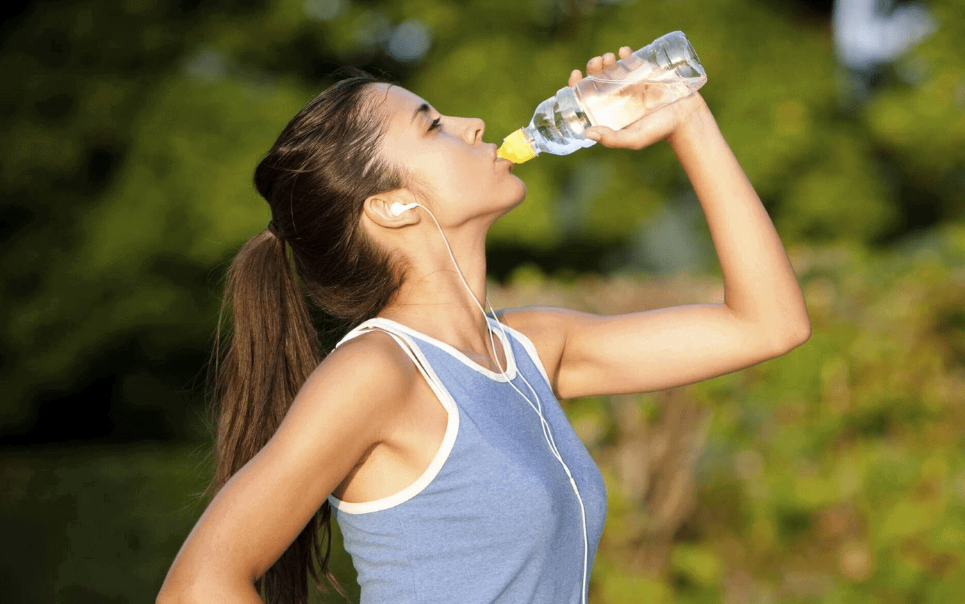 Девушка пьет воду во время тренировки